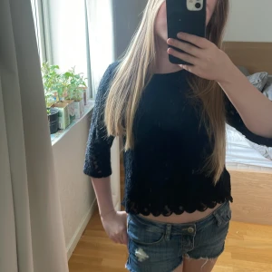 Svart blus med spetsdetaljer - Säljer en svart blus med fina spetsdetaljer och vågig kant nertill. Blusen har trekvartsärm och är lätt genombruten i materialet vilket ger en elegant look. Perfekt att styla med jeans eller kjol. Från h&m i storlek 158 men sitter som Xs/S!