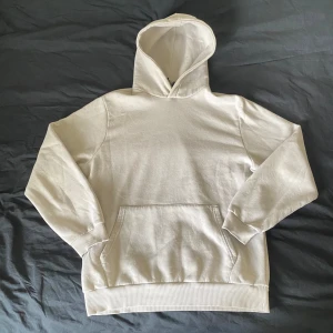 Hoodie - Säljer en stilren vit hoodie från boohooMAN. Den har en klassisk design med en stor ficka framtill och en bekväm huva. Perfekt för en avslappnad look.