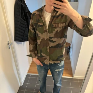 Camouflage mönstrad overshirt - Säljer en cool camouflage skjorta från Valiant Clothing. Skjortan har en klassisk krage och knäppning framtill. Perfekt för en avslappnad stil med sina långa ärmar och praktiska bröstfickor. Storlek M. Sitter perfekt på mig 185cm🙌