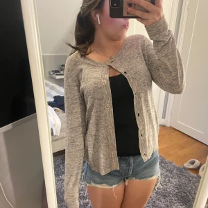 Grå kofta från Zintz - Säljer en stilren grå kofta från Zintz med knappar framtill. Perfekt för lager-på-lager och passar till många olika outfits. Den har en mjuk och bekväm känsla.