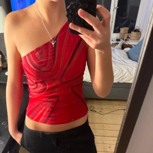 Röd one shoulder topp med mönster - Märket är new look, ingen storleks lapp men jag skulle säga att den passar xs-m