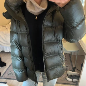 Mörkgrön pufferjacka från Massimo Dutti - Säljer min superfina mörkgrön pufferjacka med stor huva och dragkedja framtill. Jackan har långa ärmar och är vadderad för extra värme. Perfekt för kyliga dagar och har en modern, oversized passform. Det finns två små hål på armen som enkelt går att fixa, bara att skriva för fler bilder!🤍