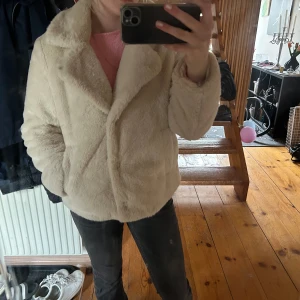 Beige pälsjacka  - Säljer en fluffig och mjuk beige pälsjacka från Noless i storlek S. Jackan har en bred krage, lång ärm och stängs framtill. Perfekt för dig som vill ha en stilren och mysig look under kyligare dagar.