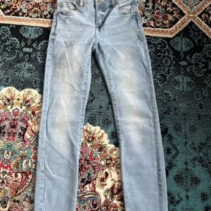 Ljusblå jeansbyxor från lager 157 - Säljer ett par ljusblå jeansbyxor från 157 med klassisk femficksdesign och raka ben. Jeansen har normal passform och är tillverkade i denim med snygga slitningar framtill. Perfekta för en avslappnad stil. För barn som är 8-9 år gammal.