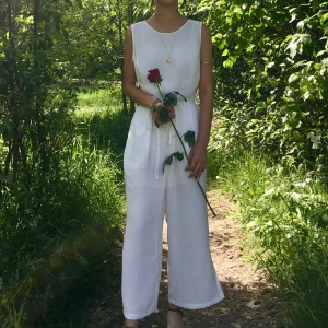 Vit byxdress med knytband i midjan - Säljer en vit byxdress med fickor och knytband i midjan. Byxdressen har ärmlös design och breda ben.