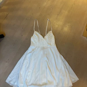 Studentklänning  - Vit studentklänning i strl m. Från bubbleroom och helt ny då den är använd 1 gång. Spetsdetalj  och knyt band bak samt dragkedja och en underkjol. Skriv om du vill ha bild på