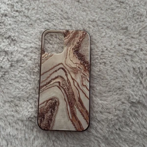 Mobilskal med marmormönster i beige och brunt. iPhone 12 mini - Säljer ett mobilskal med snyggt marmormönster i beige och bruna toner. Skalet har en glansig yta och är gjort av silikon. Bra skick endast använd fåtal gånger. För iPhone 12 mini