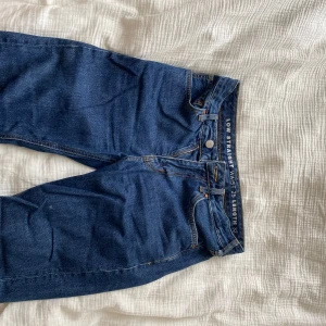 Blå jeans med låg midja och raka ben - Säljer ett par klassiska blå jeans med låg midja och raka ben. Jeansen har fem fickor, knapp- och dragkedjegylf samt tydliga sömmar. Perfekta för en avslappnad stil.