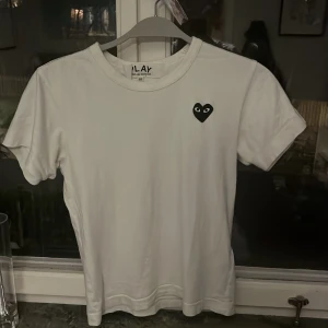 Vit t-shirt från Comme des Garçons  - Hej säljer min Vita t-shirt från Comme des Garçons.str xxs köptes förra sommaren säljer pga för liten för mig som e 163cm är xxs men comme de garcon är små i storlek så passar mindre så skulle säga att den passar nån mellan 150cm-160cm. Köptes för ungefär 1000kr från CETTIRE mitt pris 549. T-shirten är i bra skick och perfekt till sommaren  kontakta om ni har frågor!😊