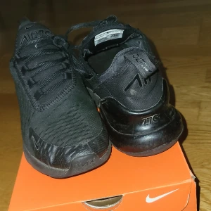 Svarta Nike Air Max 270 sneakers - Säljer ett par helsvarta Nike Air Max 270 sneakers med tydlig Air Max-detalj i sulan och diskret Nike-logga på sidan. Skorna har snörning och en sportig design som passar perfekt till streetwear och vardagsoutfits.