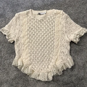 Vit topp med volang från Zara - Superfin vit blus från Zara med korta ärmar och volangdetaljer längs nederkanten och ärmsluten. Endast använd 2 gånger. Perfekt topp till sommaren.