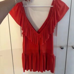 Mörk-orange volangtopp från Zara - Säljer en mörk-orange topp från Zara med djup v-ringning och volangdetaljer längs halsringningen och nederkanten. Den är i storlek S och sann i storleken!