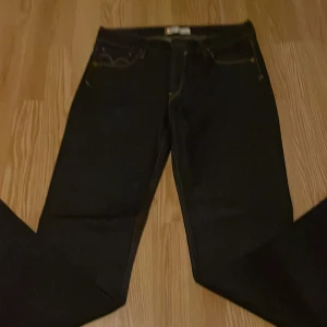 Mörkblå Levis jeansbyxor - Säljer ett par klassiska mörkblå Levis jeans med raka ben och kontrastsömmar. Byxorna har fem fickor och Levis ikoniska läderpatch bak i midjan. Perfekta för dig som gillar tidlös denimstil.