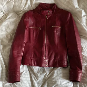 Vinröd skinnjacka - Vinröd jacka i äkta läder från livelo med silverfärgade detaljer, köpt secondhand. Jackan har en pytteliten defekt vid insidan av ena armen, se sista bilden. Färgen syns bäst på bild fyra🍒🍒