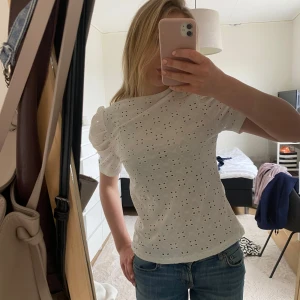 Vit broderad blus med puffärm - Superfin vit blus med broderade hålmönster och puffärmar. Toppen har en rund halsringning och är gjord i ett lätt och luftigt material, perfekt för varmare dagar. Snygg till både jeans och kjol! Man får både den vita och den gröna.