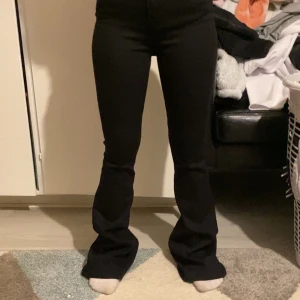 Svarta bootcut byxor - Snygga svarta byxor med bootcut passform och hög midja. Byxorna har en tight passning upptill och blir vidare nedtill vid benen. Perfekta för en trendig och stilren look.