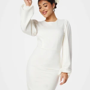 Vit långärmad klänning med puffärmar - Säljer en elegant vit klänning med långa puffärmar och rund halsringning. Klänningen har en figurnära passform och är perfekt för speciella tillfällen. Enkel men stilren design som ger en sofistikerad look.