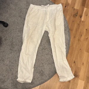 Vita linnebyxor från H&M - Säljer ett par vita linnebyxor från H&M med normal passform och dragsko i midjan. Dem har en fläck bak på.