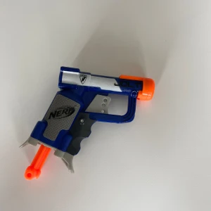 Nerf Jolt Blaster - Säljer en kompakt och smidig Nerf Jolt blaster i blå och orange plast. Perfekt för snabba dueller och enkel att ta med sig. Blastern har en tydlig JOLT-logga och klassisk Nerf-design.
