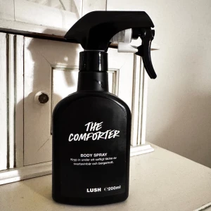 The Comforter Body Spray från Lush - En svart sprayflaska med The Comforter Body Spray från Lush. Doften har inslag av svartvinbär och bergamott. Flaskan rymmer 200 ml och har en praktisk sprayfunktion för enkel applicering. Ca 95% kvar!