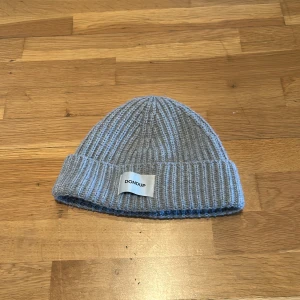 Grå ribbstickad mössa från Dondup - Snygg grå ribbstickad mössa från Dondup med uppvikt kant och diskret logotyp framtill. Tillverkad i mjukt material som håller dig varm och passar perfekt till kalla dagar.