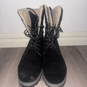 Svarta vinterkängor från McKinley Stella - Svarta kängor från McKinley, modell Stella, med grov sula och snörning. Utsidan är i mocka och insidan är fodrad med mjukt, ljust fleecefoder. Perfekta för kalla dagar och har en robust design som ger bra grepp.