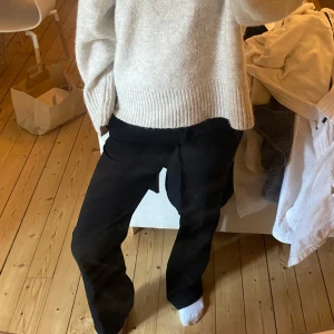 Svarta kostymbyxor med knytband - Säljer ett par svarta kostymbyxor. Byxorna har en rak passform och är perfekta för en stilren look. De är lågmidjade och har en klassisk design utan synliga detaljer som knappar eller dragkedja framtill.