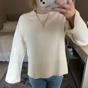 Vit stickad tröja med ribbade detaljer - Säljer en stilren vit stickad tröja med breda ribbade muddar vid ärmslut och nederkant. Tröjan har rund halsringning och lång ärm, perfekt för en kallare dag!💕