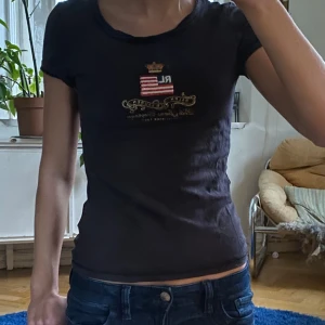 T-shirt från Ralph Lauren med tryck - Säljer en jättesnygg svart tight t-shirt från Ralph Lauren i storlek XS. Skriv om du har frågor!