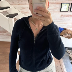 Mörkblå kaschmir hoodie med dragkedja från Soft Goat - Mysig mörkblå kaschmir hoodie från Soft Goat med dragkedja framtill och två fickor. Näst intill oanvänd, inga synliga skador men möjligtvis lite nopprig här och där. Dock inget som direkt är synligt vid användning:)