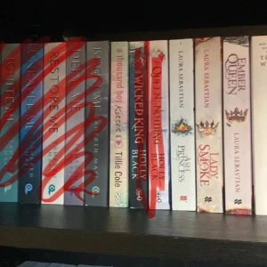 A Thousand Boy Kisses av Tillie Cole - En gripande roman med titeln 'A Thousand Boy Kisses' av Tillie Cole. Boken har ett ljust omslag med hjärtan och rosa detaljer. Perfekt för dig som gillar romantik och känslosamma berättelser.