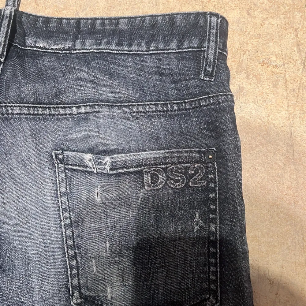 Säljer ett par svarta jeansbyxor från Dsquared2 i storlek 50. Jeansen har slitna detaljer, diskreta hål och patchar framtill samt broderad DS2-logga på bakfickan. Klassisk femficksmodell med knappgylf och raka ben.. Farkut & Housut.
