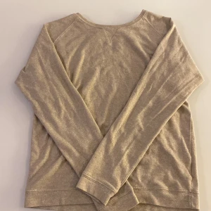 Beige långärmad tröja i bomull - En enkel och mjuk beige långärmad tröja i bomull. Tröjan har rund halsringning och raka ärmar, perfekt för lager-på-lager eller som basplagg. Passar till det mesta och är riktigt skön att ha på sig.