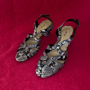 Ormskinns klackskor  - Säljer ett par snygga klackskor i svartvitt ormskinnsmönster och öppen tå.  Perfekta för dig som vill sticka ut med ett coolt mönster.