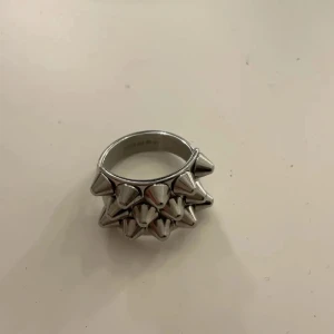 Silverfärgad ring med nitar - Cool ring i silverfärg med två rader av spetsiga nitar runt hela ringen. Perfekt accessoar för dig som gillar en edgy och unik stil.