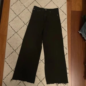 Svarta wide leg jeans från gina tricot Perfect Jeans - Svarta jeans med wide leg-modell från Perfect Jeans. Byxorna har råa, avklippta benslut och klassisk femficksdesign. Perfekta för dig som gillar en avslappnad och trendig stil.