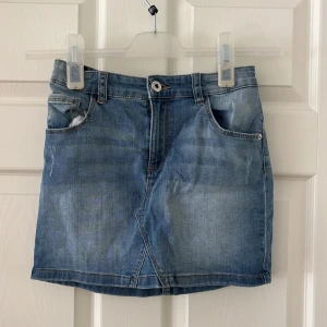 Blå jeanskjol från LAB Industries - Snygg blå jeanskjol från LAB Industries med klassisk femficksdesign, knapp och dragkedja framtill. Kjolen har en lätt tvättad look med coola sömdetaljer och bakfickor. Perfekt till sneakers eller boots för en chill stil.