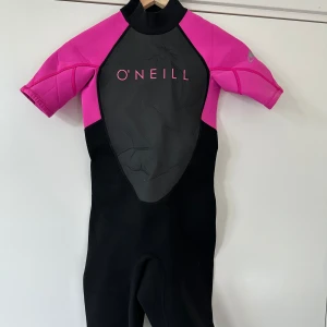 Våtdräkt för barn 10-12 år - Välgjord O'Neill Reactor II våtdräkt för barn, storlek 141-147cm. Perfekt såväl för tävlingssport som vattenlek.   Material: Utsidan paneler: 83% nylon, 17% spandex. Paneler på utsida höger krage: 95% nylon, 5% spandex. Insidan paneler: 100% nylon. Alla paneler fästa på neopren. Mycket gott skick.  Hämtas i Stockholm eller skickas mot porto. 