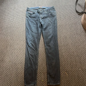 Mörkblå slim jeans Tommy Hilfiger - Snygga mörkblå skinny jeans från Tommy Hilfiger Denim med klassiska fem fickor och diskret logga på bakfickan. Jeansen har normal passform och är tillverkade i stretchigt denimtyg för extra komfort. Perfekta för en clean och stilren look. Använd fåtal ggr