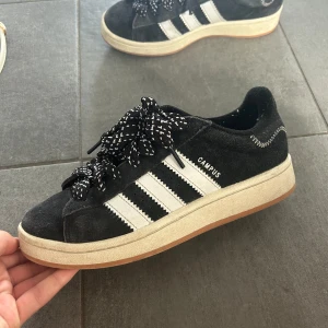 Adidas Campus svarta sneakers mocka - Svarta Adidas Campus , i en ganska unik tråd , medföljer en vit tråd också .Skorna är inte tvättade därför de ser lite smutsiga ut .Skriv innan ni köper .Köpta ifrån Adidas.Haft de sedan april .Pris kan diskuteras 