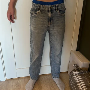 Blå straight jeans från Lindex - Säljer ett par blå tvättade jeans från Lindex med klassisk femficksdesign och raka ben. Jeansen har normal passform och midja, tillverkade i mjukt denimtyg som ger en avslappnad vibe. Perfekta för dig som gillar en enkel och tidlös look.