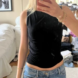 Svart ärmlös linnetopp - Ett svart linne från Gina Tricots soft touch linje, som är vääldigt skönt. Toppen är tight och har en enkel, clean look som passar till allt. Mjuk och stretchig i materialet för en bekväm passform.