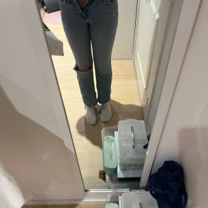  ljusblå jeans med hål - Ljusblå jeans med klassisk rak passform och hög midja. Jeansen har ett snyggt hål på ena knät för en trendig look. Tillverkade i jeansmaterial med fem fickor. Från Gina tricot i stolek 32