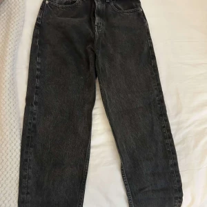 Svarta jeans från Tommy Jeans - Snygga svarta jeans från Tommy Jeans i klassisk femficksmodell. Jeansen har raka ben och hög midja, tillverkade i robust denim med diskret tvättad look. Perfekta för dig som gillar en tidlös och clean stil.