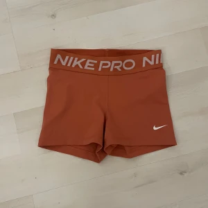 Nike Pro träningsshorts - Snygga o aprikos färgade  Nike Pro shorts med medel midja och bred resår med logga. Tight passform och korta ben, perfekta för träning eller sport. Materialet är stretchigt syntet som andas och ger bra rörelsefrihet. 