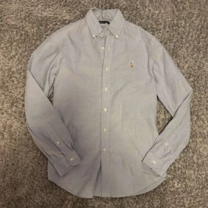 Ljusblå skjorta från Ralph Lauren - Säljer nu en ljusblå skjorta från Ralph Lauren som är custom fit. Skjortan har ett litet hål på armen men detta syns knappt inte vid användning! Hojta till om du har någon fråga!