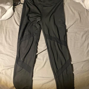 Svarta leggings med paneldetaljer - Svarta leggings med snygga paneldetaljer längs benen. De har en tight passform och är perfekta för träning eller chill. Materialet känns mjukt och stretchigt, vilket gör dem riktigt bekväma att ha på sig. Rekommenderas för barn från 10-13 år beroende på om man har korta eller långa ben