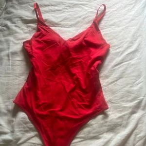 Säljer min snygga body pågrund att den inte kommit till användning  - Snygg röd body med smala axelband och v-ringad front. Modellen är enkel och stilren med hög benskärning som ger en modern look. Materialet känns mjukt och följsamt mot kroppen. Har aldrig använt 🩷priset kan diskuteras 