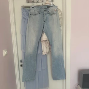 Ljusblå Replay jeans bootcut - Säljer ett par ljusblå jeans från Replay med klassisk femficksdesign och bootcut-ben. Jeansen har slitna detaljer vid bensluten och snyggt tvättad look. De har lite fläckar, men tänker att det är perfekta om man vill använda dom till att sy nått annat!!