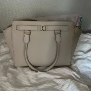 Handväska💞 - Snygg beige/ljusrosa handväska från Don Donna💞 Väskan har dragkedja, ytterfack med dragkedja och flera innerfack. Väskan har några få defekter ( se bild 3-5) några små fläckar inuti väskan. Långt band till väskan medföljer. Bredd: 35 cm, höjd: 25 cm💞Pris kan diskuteras 